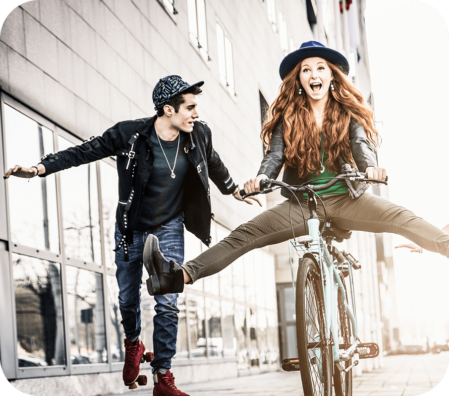 A group of young people together on the sidewalk, one of them is riding a bike.