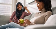 Teens sitting together. On of them is holding a pear