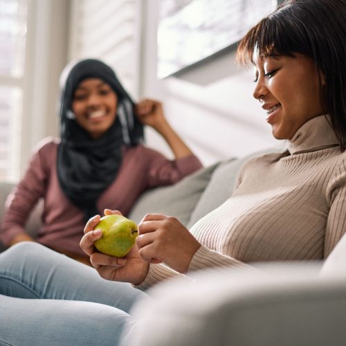 Teens sitting together. On of them is holding a pear