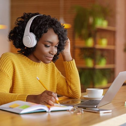 Smiling girl using laptop with wireless headphones